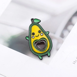 Detail showing a cartoon avocado enamel pin with a heart-shaped hollow core and a cute face