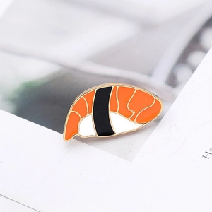 Detail shot of a creative sushi enamel pin with orange and black alloy drip oil craft