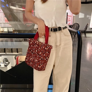 Dettaglio borsa a mano in velluto rosso a fiori con manici in nastro e bottone in metallo