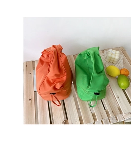 Détail de sacs baguette à cordon orange et vert sur un support en bois minimaliste
