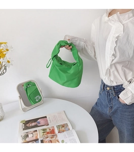 Sac baguette vert minimaliste posé sur une table avec des fleurs et un magazine