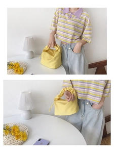 Détail d'un sac baguette en toile jaune porté par un mannequin dans un cadre épuré
