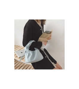 Gros plan d'un sac baguette bleu clair minimaliste porté par un mannequin en situation réelle