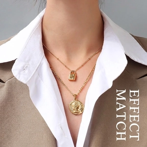 Layered 18K gold titanium steel necklace featuring padlock and coin charms on a model