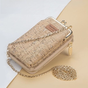 Detailed macro shot of natural cork texture and golden kiss-lock of women's crossbody bag