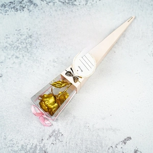 Close-up of a 24K gold foil rose inside a white gift box with pink ribbon and gift card