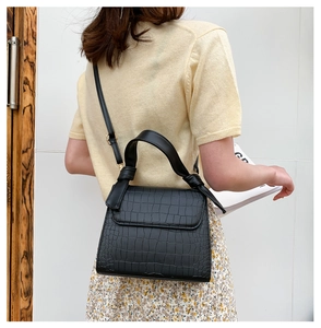 Detail of black crocodile pattern leather handbag with wide handle and shoulder strap
