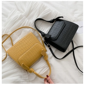 Detail view of yellow and black crocodile pattern handbags on white fabric background