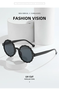 Detailed close-up of round black wave-edge sunglasses with UV400 protective lenses