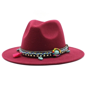 Close-up of wine red wool fedora with turquoise beads, tassels and metal pendant