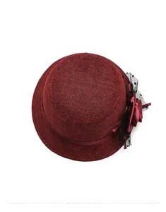 Detail of burgundy linen bucket hat featuring large fabric flower and polka dot mesh veil