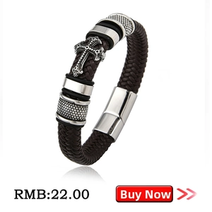 Detailed close-up of brown braided leather bracelet with vintage silver cross charm