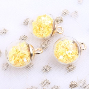 Close-up of clear crystal glass ball pendants with yellow star sequins and gold metal rings