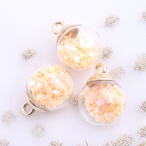 Macro shot of glass ball pendants with star sequins and gold hooks for DIY jewelry