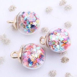 Detail of transparent glass globe pendants with colorful star sequins and gold hooks