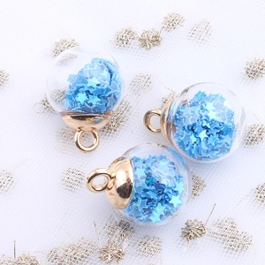 Detail of glass globe charms with blue star sequins and golden metal caps for DIY jewelry