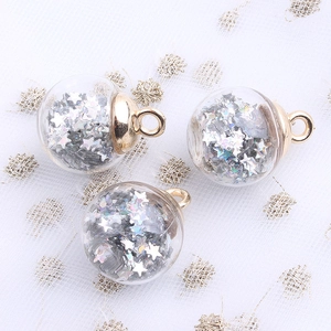 Close-up of three clear glass ball pendants with silver star sequins and gold metal loops