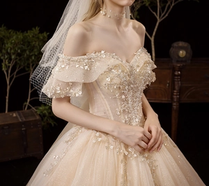 Detail of champagne off-shoulder wedding dress with intricate sequins and 3D floral lace