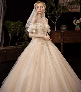 Close-up of off-the-shoulder champagne wedding dress with intricate beadwork and lace