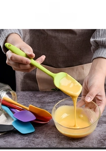 Action shot of silicone spatula mixing batter in a glass bowl for baking and cooking