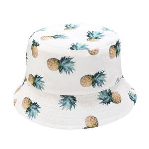 Detailed view of white bucket hat with yellow pineapple fruit patterns and cotton fabric