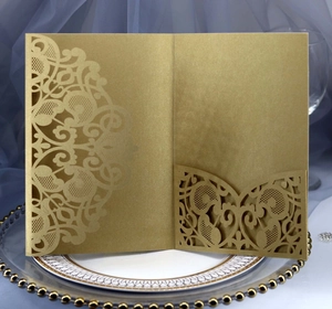 Detail of golden laser-cut invitation sleeve with baroque patterns on a decorative plate