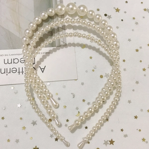 Detailed close-up of three handmade pearl headbands with diverse bead sizes on mesh background