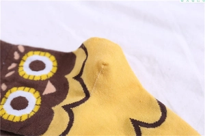 Close-up of knit density and seam craft on yellow cartoon owl socks with wavy texture