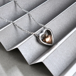 Gros plan du pendentif cœur creux bicolore en acier inoxydable argenté et or rose