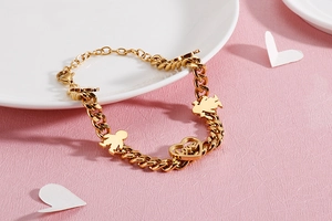 Detailed close-up of golden curb chain bracelet with heart Love charm and human figures