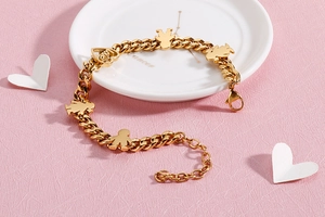 Detailed close-up of golden stainless steel bracelet with boy-girl charms and Love heart
