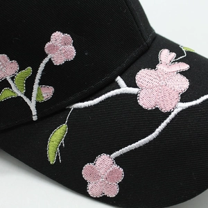 Macro detail of exquisite pink floral embroidery on a black cotton baseball cap