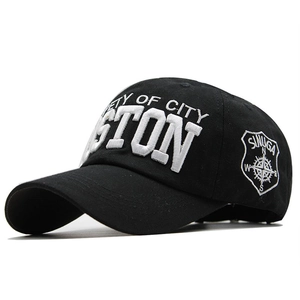 Close-up of 3D Boston embroidery and side compass patch on a black cotton baseball cap