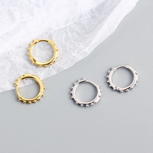 Vue détaillée des créoles polies en argent et or avec texture de rivets perlés