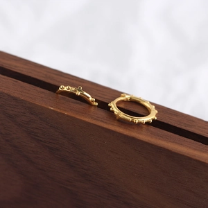 Gros plan de boucles d'oreilles créoles croix en argent 925 doré sur bois