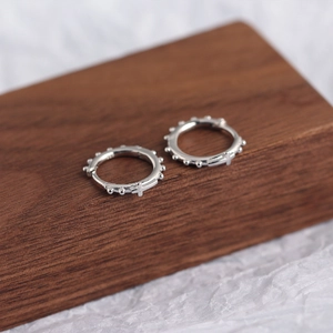 Vue macro de boucles d'oreilles en argent 925 avec bordure perlée et petite croix