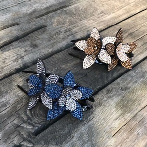 Detailed view of large rhinestone flower hair clips in blue and champagne on wood