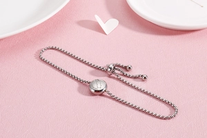 Detail of adjustable silver box chain bracelet featuring a Gemini zodiac coin charm