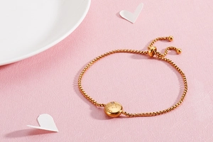 Detailed view of adjustable gold Libra zodiac bracelet with sparkling stones on pink texture