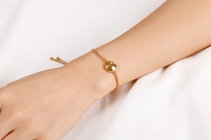 Detail view of gold adjustable zodiac bracelet with crystal pendant on wrist