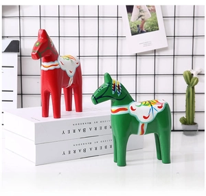 Detail of red and green painted wooden Dala horses on books in a home decor setting