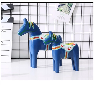 Detail of two navy Dala Horses with hand-painted folk art patterns for desk decoration