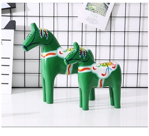Close-up of two green Dala wooden horses with colorful traditional patterns in two sizes