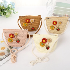 Detail of four colorful kids' straw crossbody bags with knit sunflowers and ladybugs