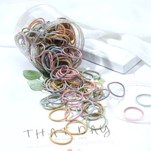 Jar of colorful elastic scrunchies on white background with green leaves decoration