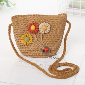 Detail of woven straw crossbody bag with colorful fabric flowers and a small ladybug
