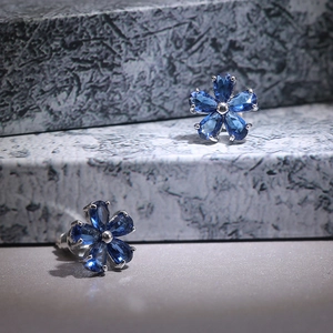 Macro detail of silver flower earrings featuring deep blue marquise-cut zircon petals