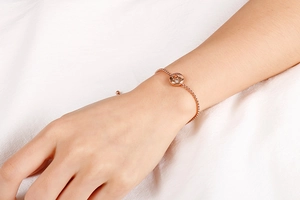 Detailed view of rose gold zodiac bracelet with crystal pendant on model wrist