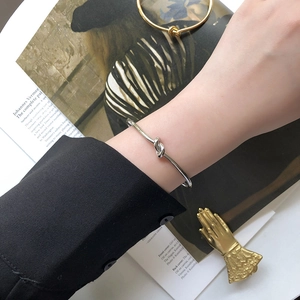 Minimalist stainless steel knot cuff bracelet with high polished finish on silver surface