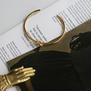 Minimalist 18K gold plated stainless steel knot open cuff bracelet on art magazine